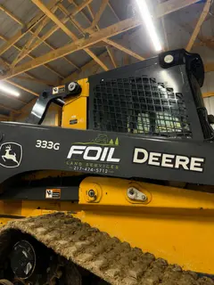 Foil Land Services branding on a John Deere 333G compact track loader